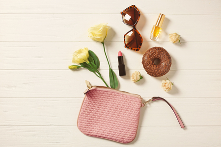 Tasty chocolate doughnut, flowers and cosmetics on white wooden backgroundの写真素材