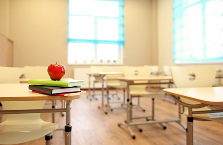 Stack of books and apple on desk at classroomの写真素材