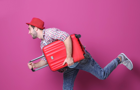 Man traveler with suitcase on color backgroundの写真素材