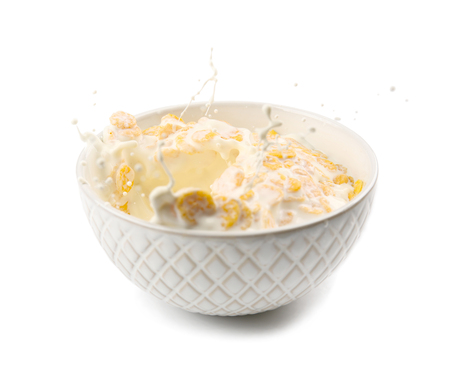 Corn flakes in bowl with milk splash on white backgroundの写真素材