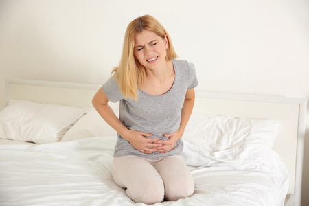 Young woman suffering from pain on bedの写真素材