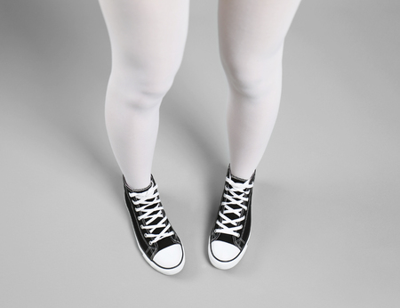 Woman in white stockings and sneakers on color backgroundの写真素材