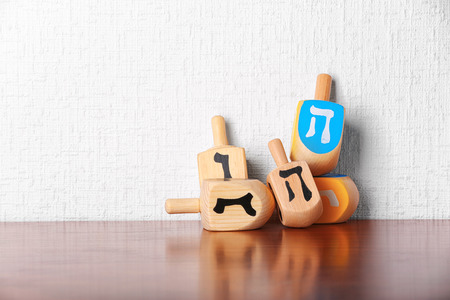 Dreidels for Hanukkah on wooden table against light textured wallの写真素材