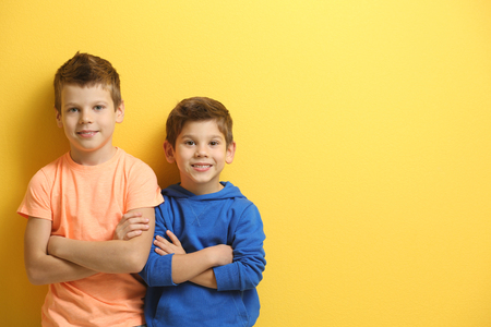 Cute little brothers standing on yellow backgroundの写真素材