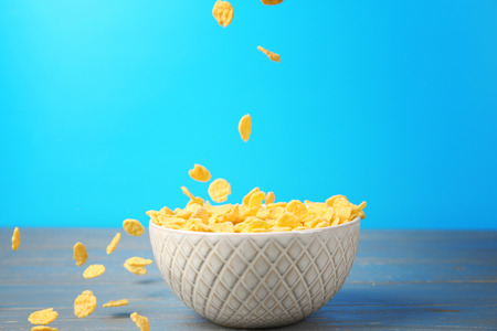 Bowl with corn flakes on blue background