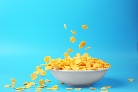 Bowl with corn flakes on blue backgroundの写真素材