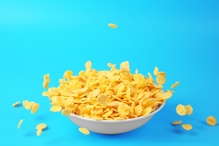 Bowl with corn flakes on blue background
