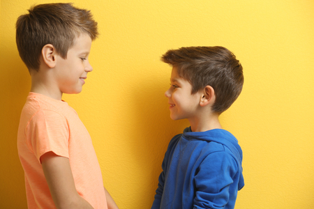 Cute little brothers standing on yellow backgroundの写真素材