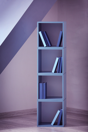 Blue wooden shelving with books on gray wall backgroundの写真素材