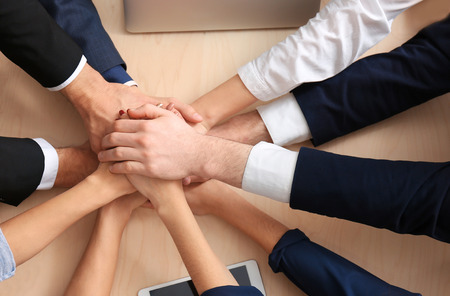 United hands of business team on table background, top view