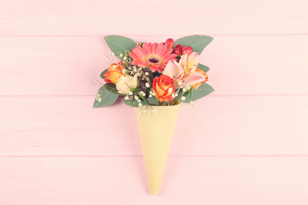 Waffle cone with composition of beautiful flowers on pink backgroundの写真素材