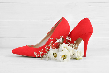 Red shoes with flowers on white wooden backgroundの写真素材