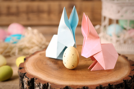Origami bunnies and Easter egg on decorative wooden stump, closeupの写真素材