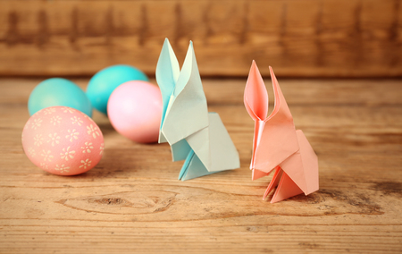 Origami bunnies and Easter eggs on wooden backgroundの写真素材
