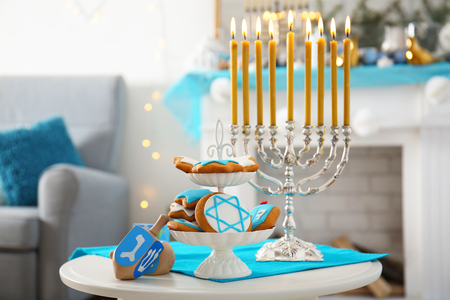 Menorah, dreidels and cookies for Hanukkah on stool in living room, closeupの写真素材