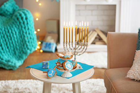 Menorah, dreidels and cookies for Hanukkah on stool in living roomの写真素材