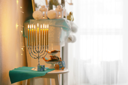 Menorah, dreidels and cookies for Hanukkah on stool in living room