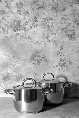 Metal pans with lids on textured wall background