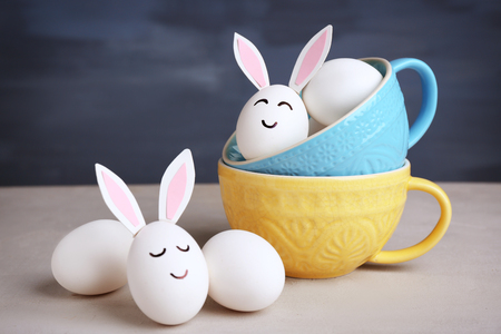 Easter eggs with paper ears on table against blue backgroundの写真素材