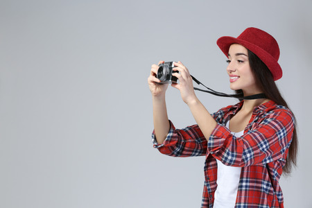 Pretty young tourist taking photo on grey backgroundの写真素材