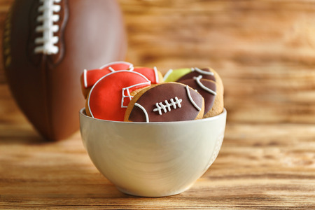 Bowl with creative cookies decorated in football style on wooden backgroundの写真素材