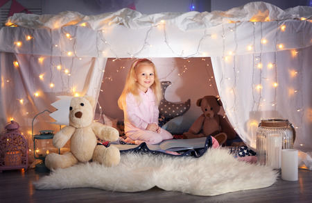 Cute little girl sitting in hovel at homeの写真素材