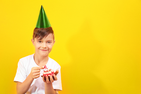 Cute boy  with birthday mini cake on yellow backgroundの写真素材