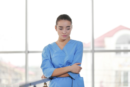 Depressed medical worker standing near banisters in clinicの写真素材