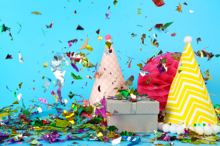 Party hats, gift with colorful confetti on color backgroundの写真素材