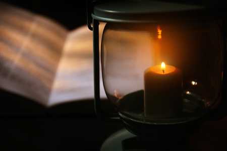 Burning candle and  Bible on tableの写真素材