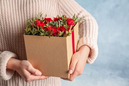 Woman holding beautiful roses in gift box, closeupの写真素材