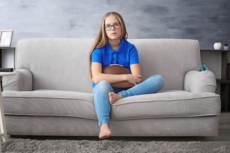Pretty teenager watching rugby on TV at homeの写真素材