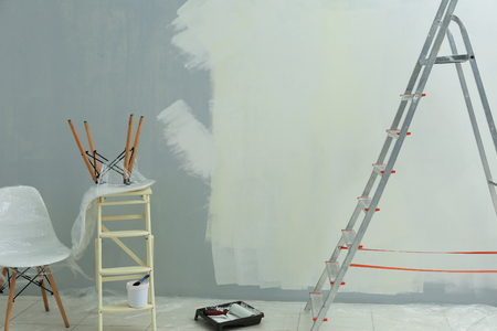 Ladder, paint and tools for making repair in empty roomの写真素材