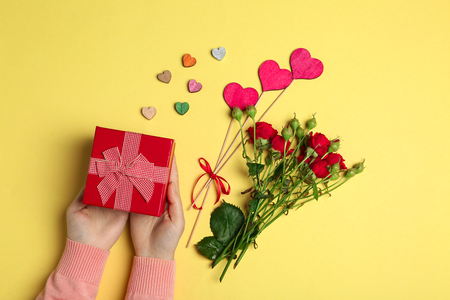 Female hands holding gift box on color backgroundの写真素材
