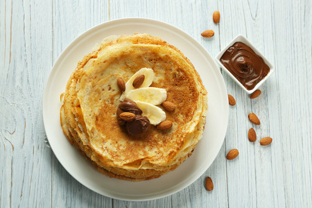 Delicious pancakes with banana and chocolate on white wooden backgroundの写真素材