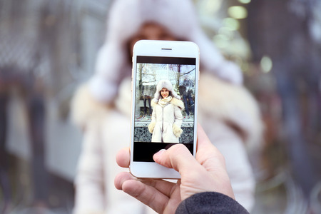 Young man taking photo of beloved girlfriend on the streetの写真素材