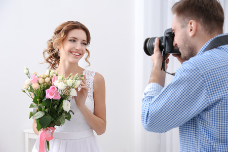 Wedding photographer taking photo of beautiful bride in studioの写真素材