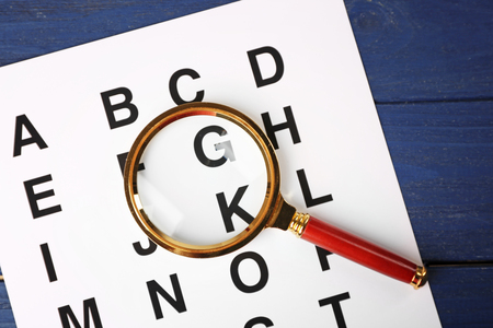 Paper with alphabet and magnifier on blue wooden backgroundの写真素材