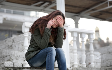 Depressed young woman sitting on stairsの写真素材