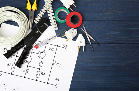 Electrician tools and schemes on wooden background