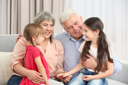 Grand parents and girls on sofa in the roomの写真素材