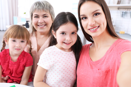 Mother, granny and girls taking selfie at kitchenの写真素材