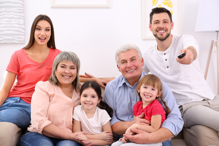 Happy family watching TV on sofa at home