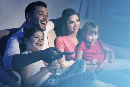 Happy family watching TV on sofa at homeの写真素材