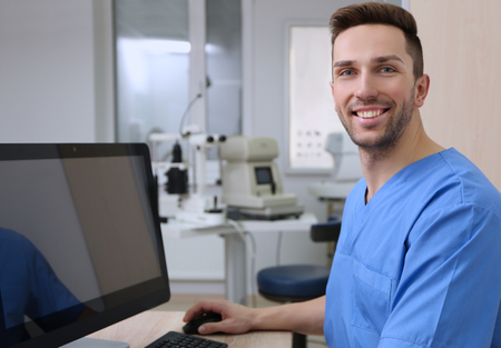 Handsome young ophthalmologist working with computer in clinicの写真素材