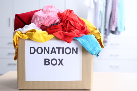 Donation box with clothes on table in the roomの写真素材