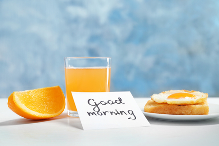 Note with phrase GOOD MORNING and tasty breakfast on tableの写真素材