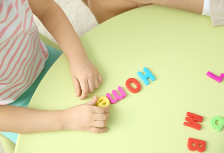 Little girl with teacher constructing word HOME on private lessonの写真素材