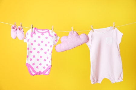Clothesline with hanging baby clothes on yellow backgroundの写真素材