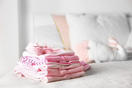 Set of baby clothes and toy on bedの写真素材
